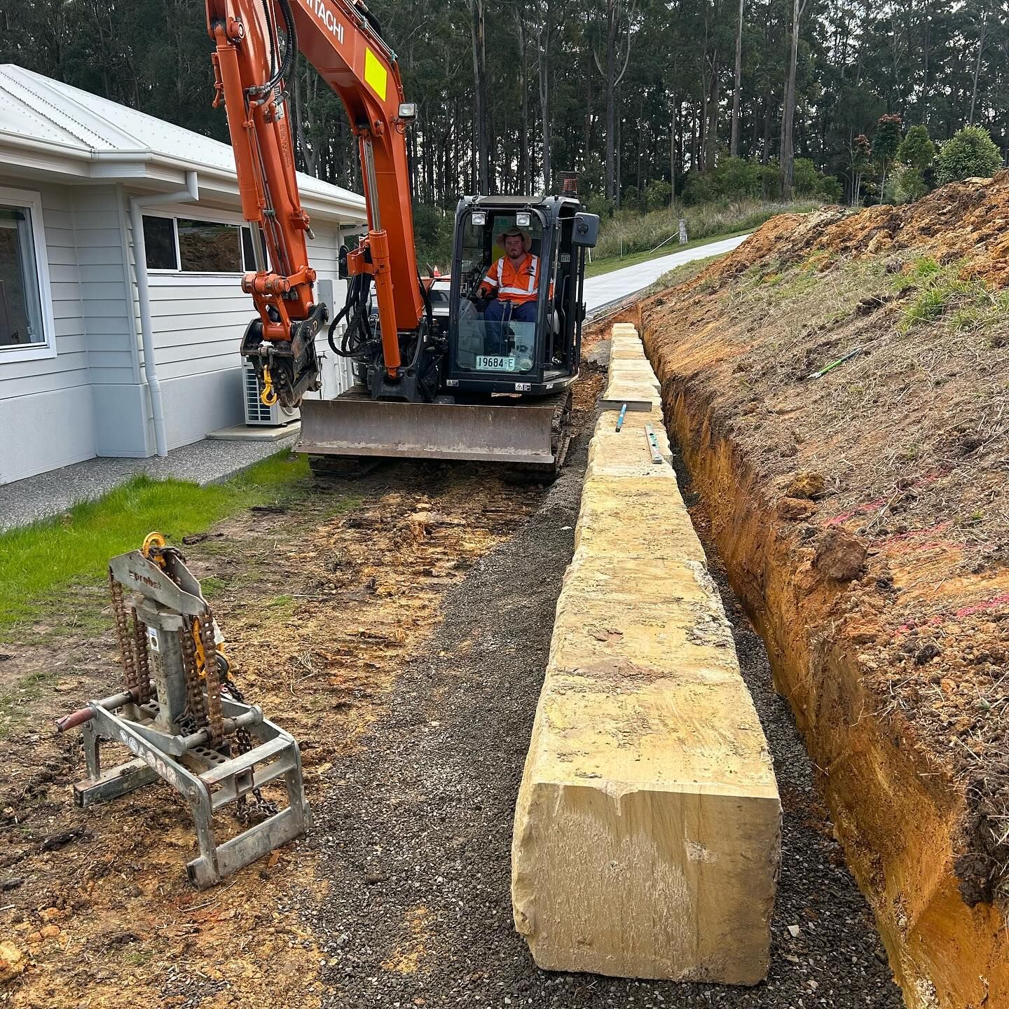 Excavator Placing a Large Stone Block in a Trench — MG Earthworks and Plant Hire in Kempsey, NSW