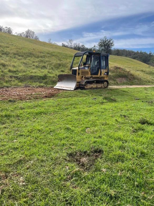 Orange excavator on a gravel surface. Metal building and blue sky in the background.