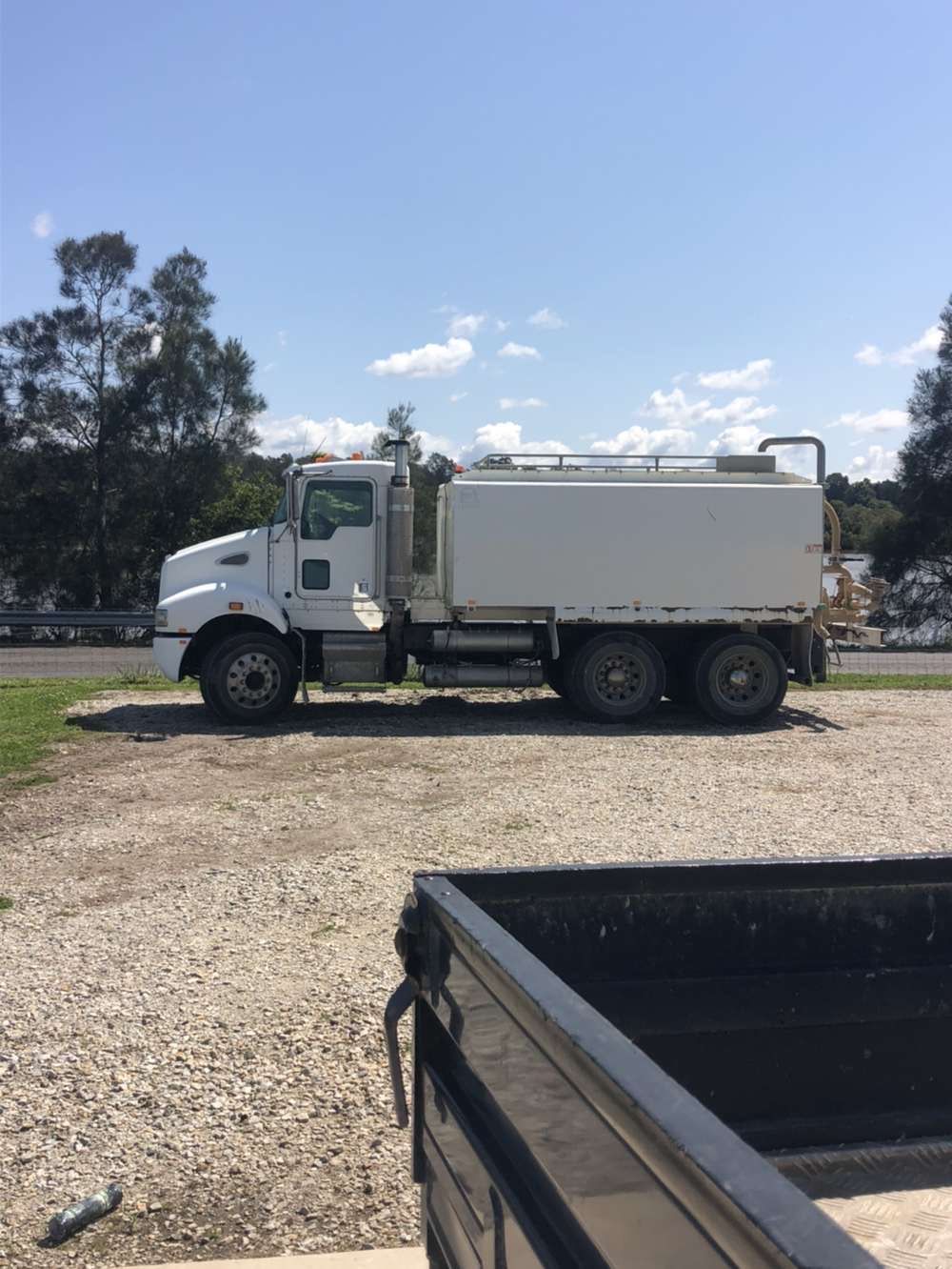 White water truck parked on gravel in a sunny outdoor setting.