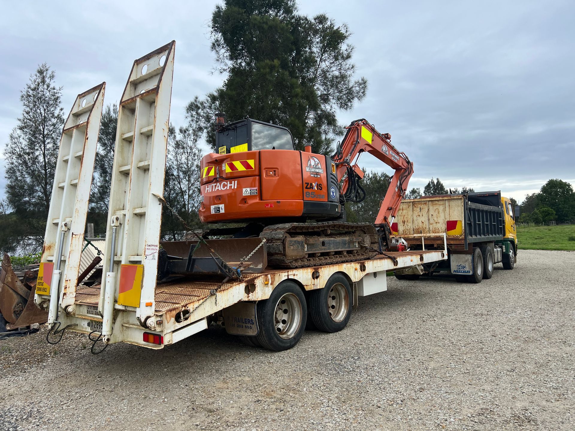 Blue excavator on tracks, near a body of water, parked.