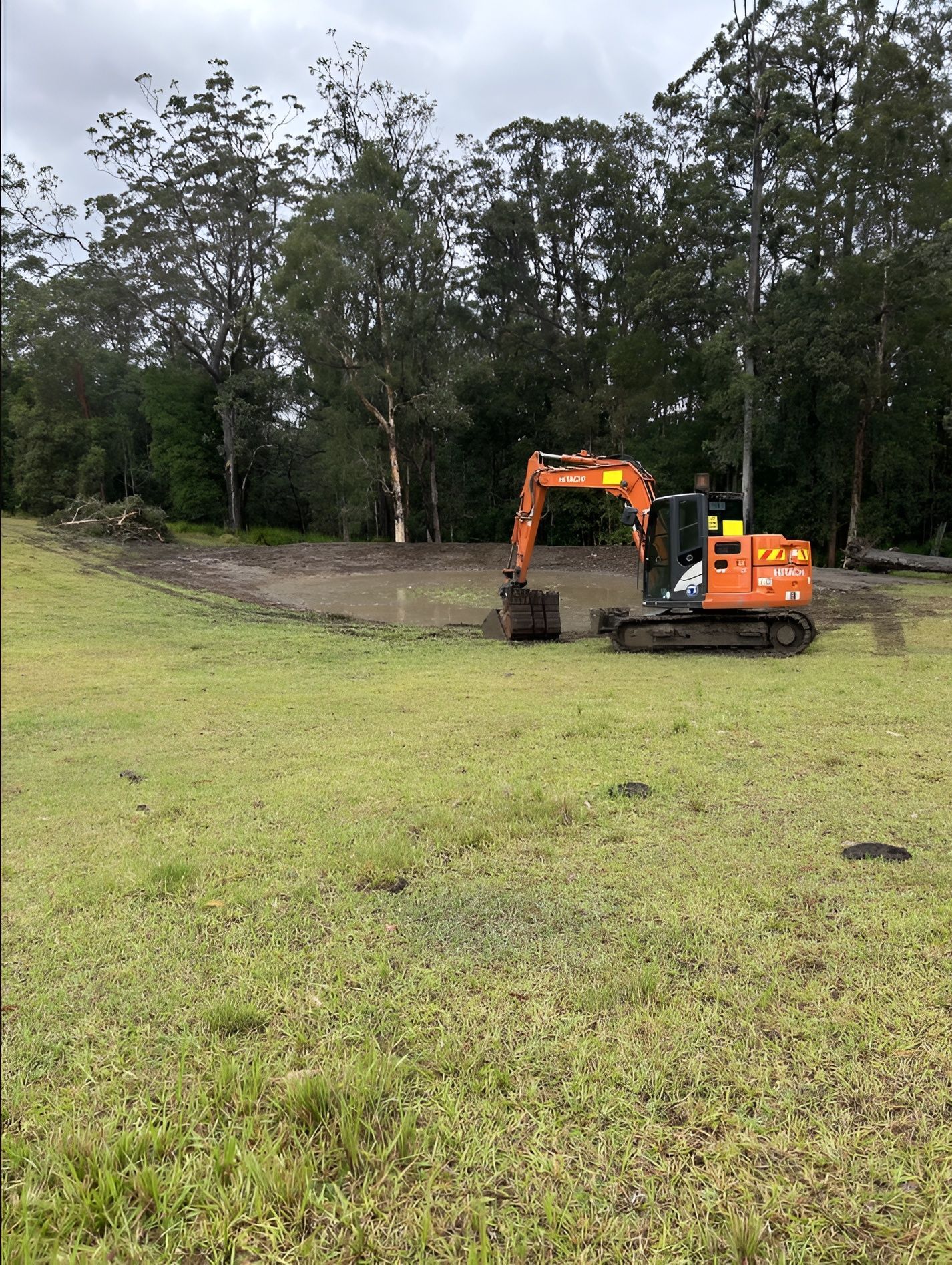 Orange Excavator in a Muddy Area, Digging in a Field — MG Earthworks and Plant Hire in Gumma, NSW