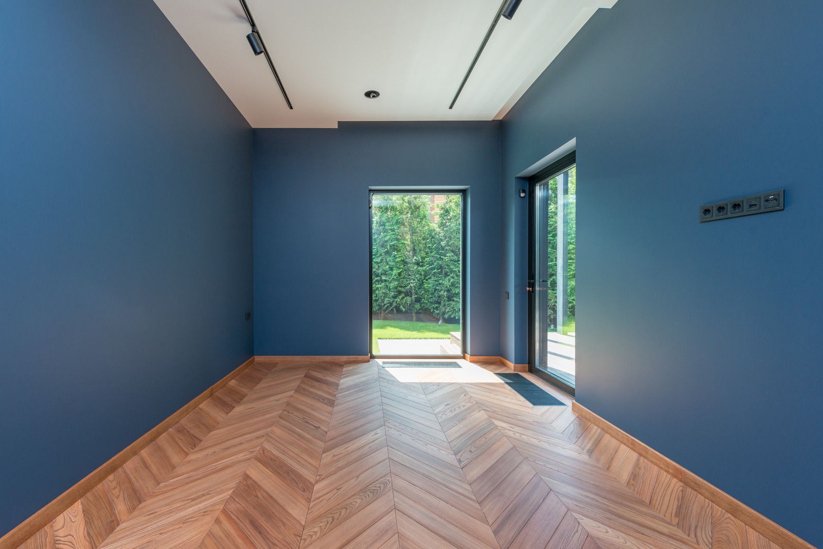 An empty room with blue walls and a wooden floor.