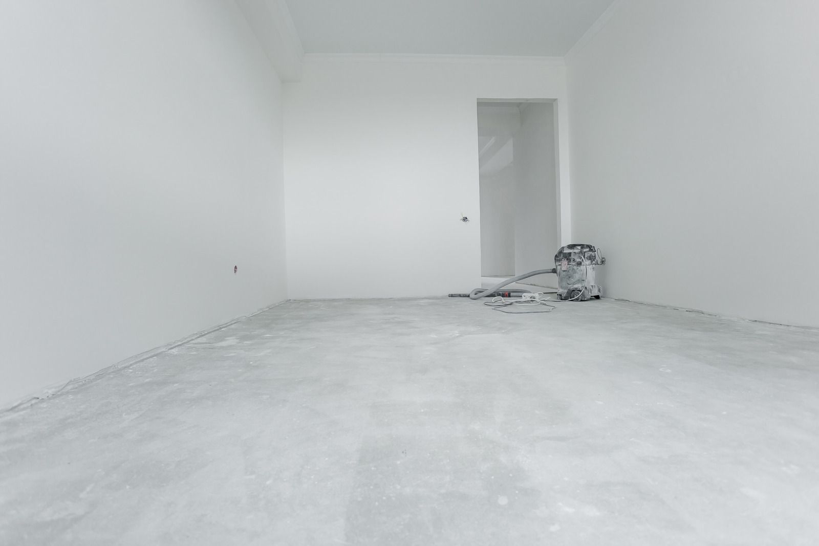 An empty room with a concrete floor and white walls.