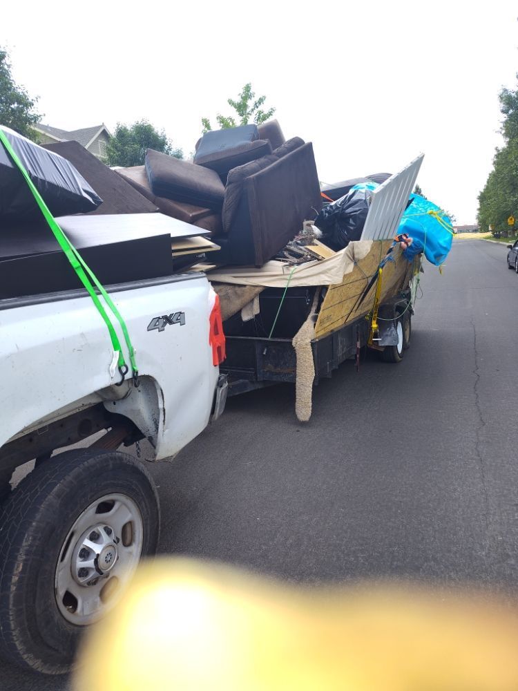 A white truck is pulling a trailer full of junk