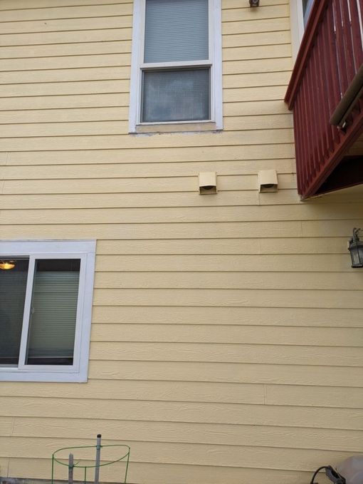 A yellow house with a red balcony and a window