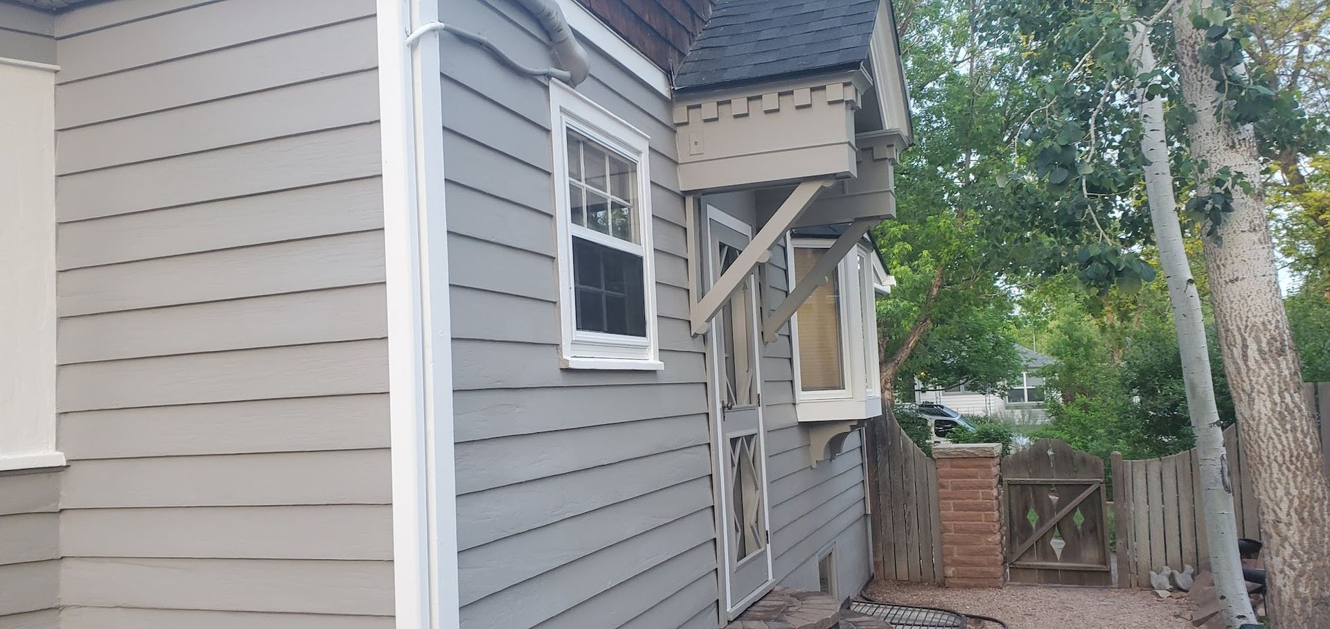 The side of a house with a window and a fence in the background.