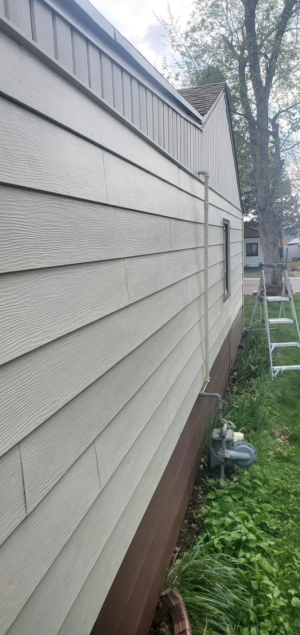 A mobile home with a white siding and brown trim is sitting in the grass.