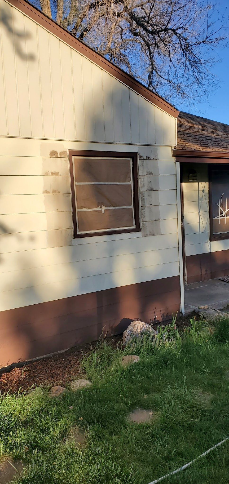 A white and brown house with a window missing.
