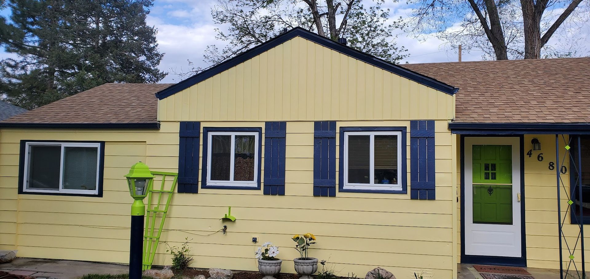 A yellow house with blue shutters and a green door.