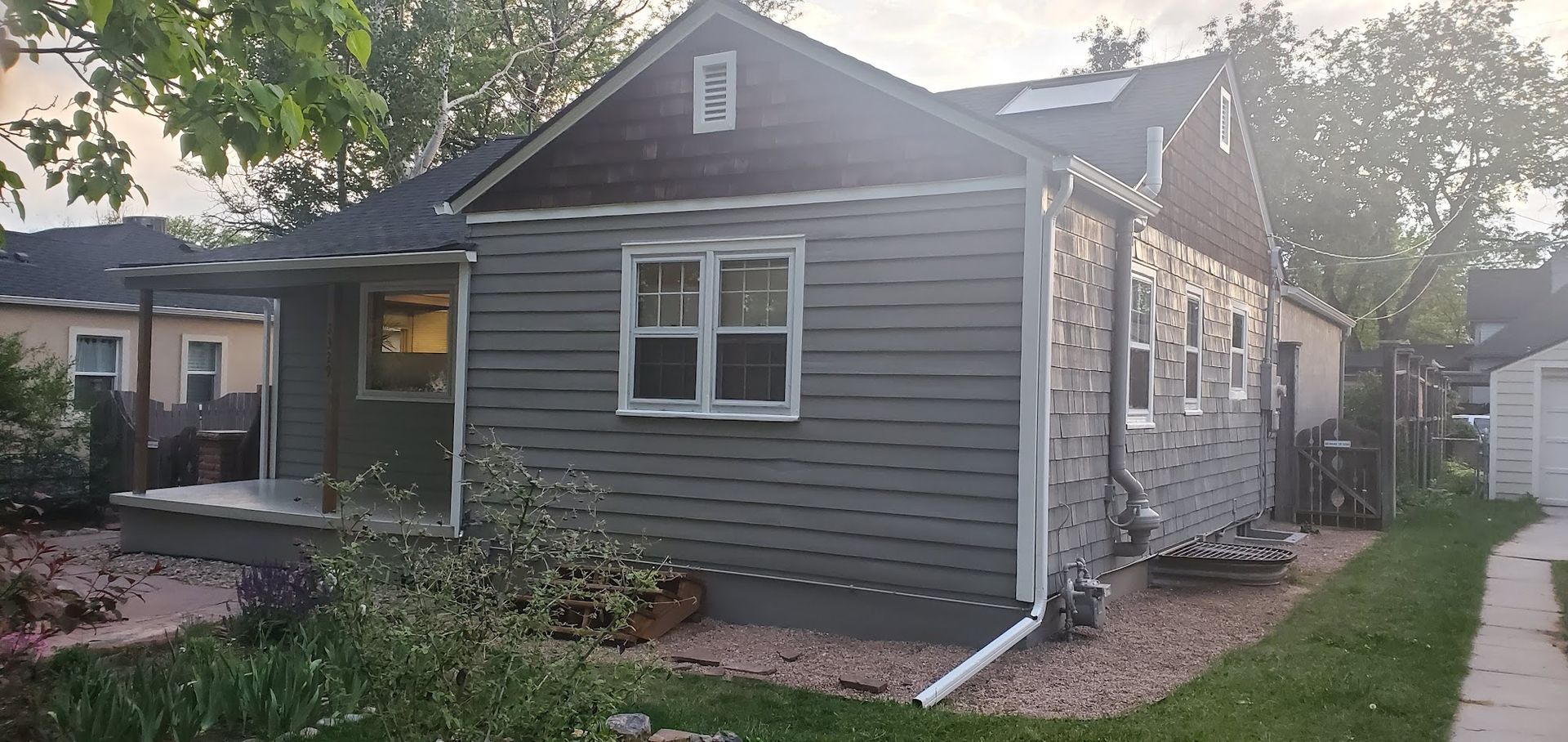 A small house with a porch and a gutter on the side of it.