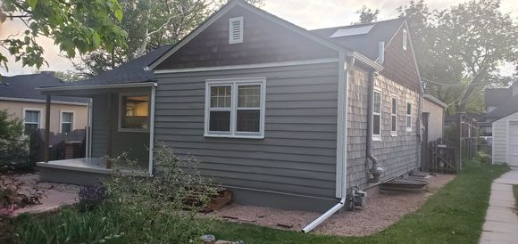 A small house with a porch and a gutter on the side of it.