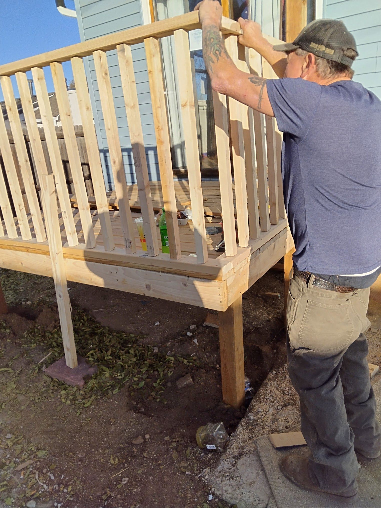 A man is working on a wooden railing on a deck.