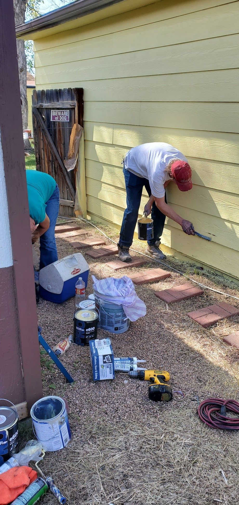 A group of men are painting a yellow house.
