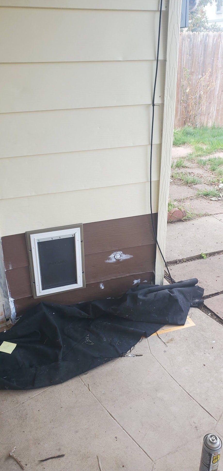 A dog door is being installed on the side of a house.