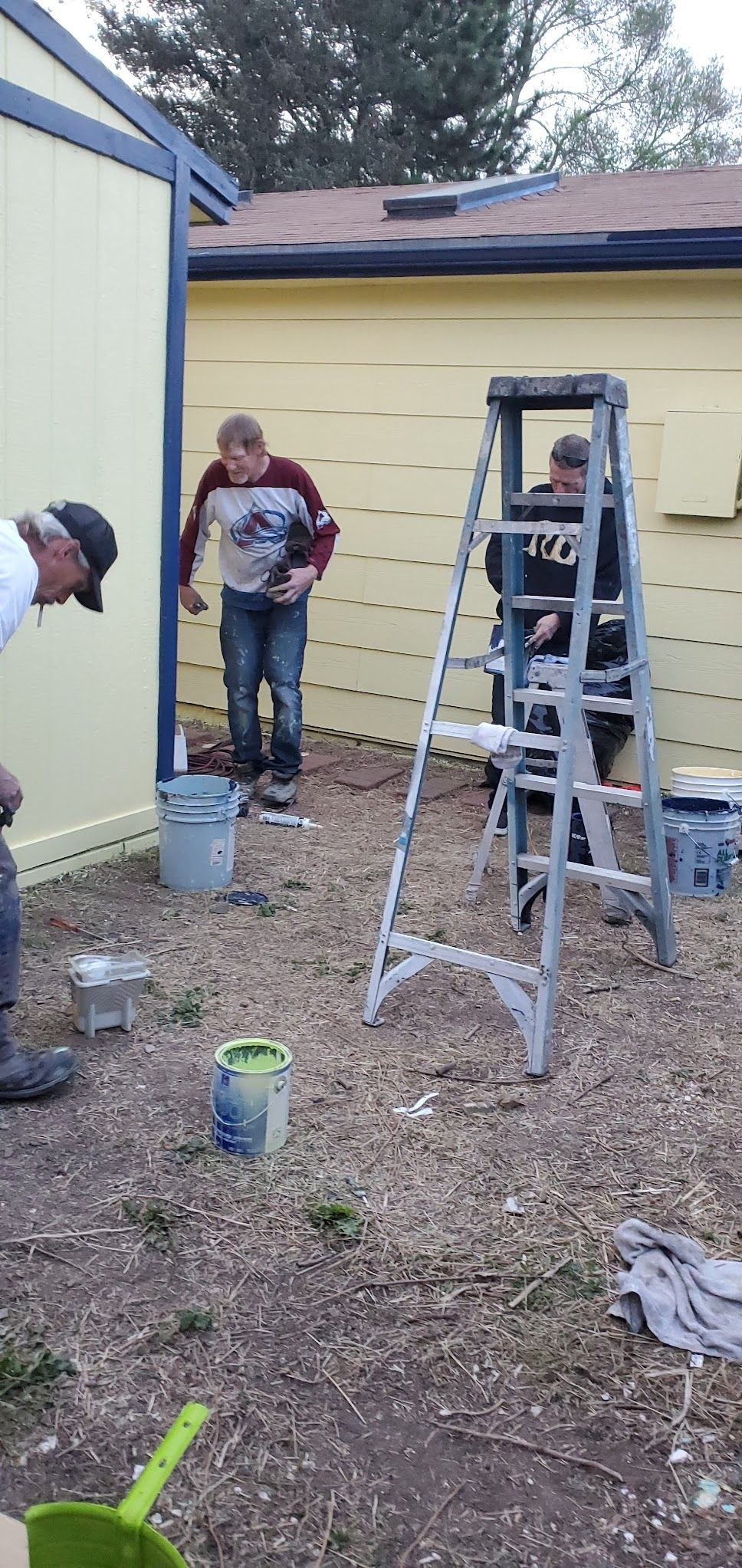 A group of people are painting a yellow building.