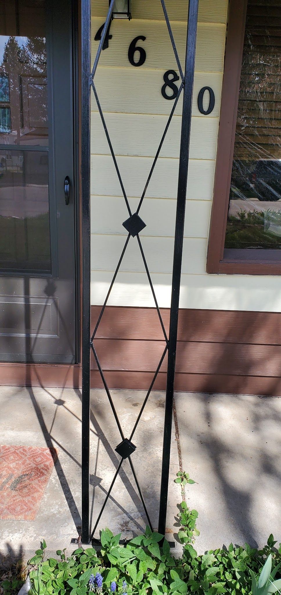 A wrought iron fence is in front of a house with the number 80 on it.