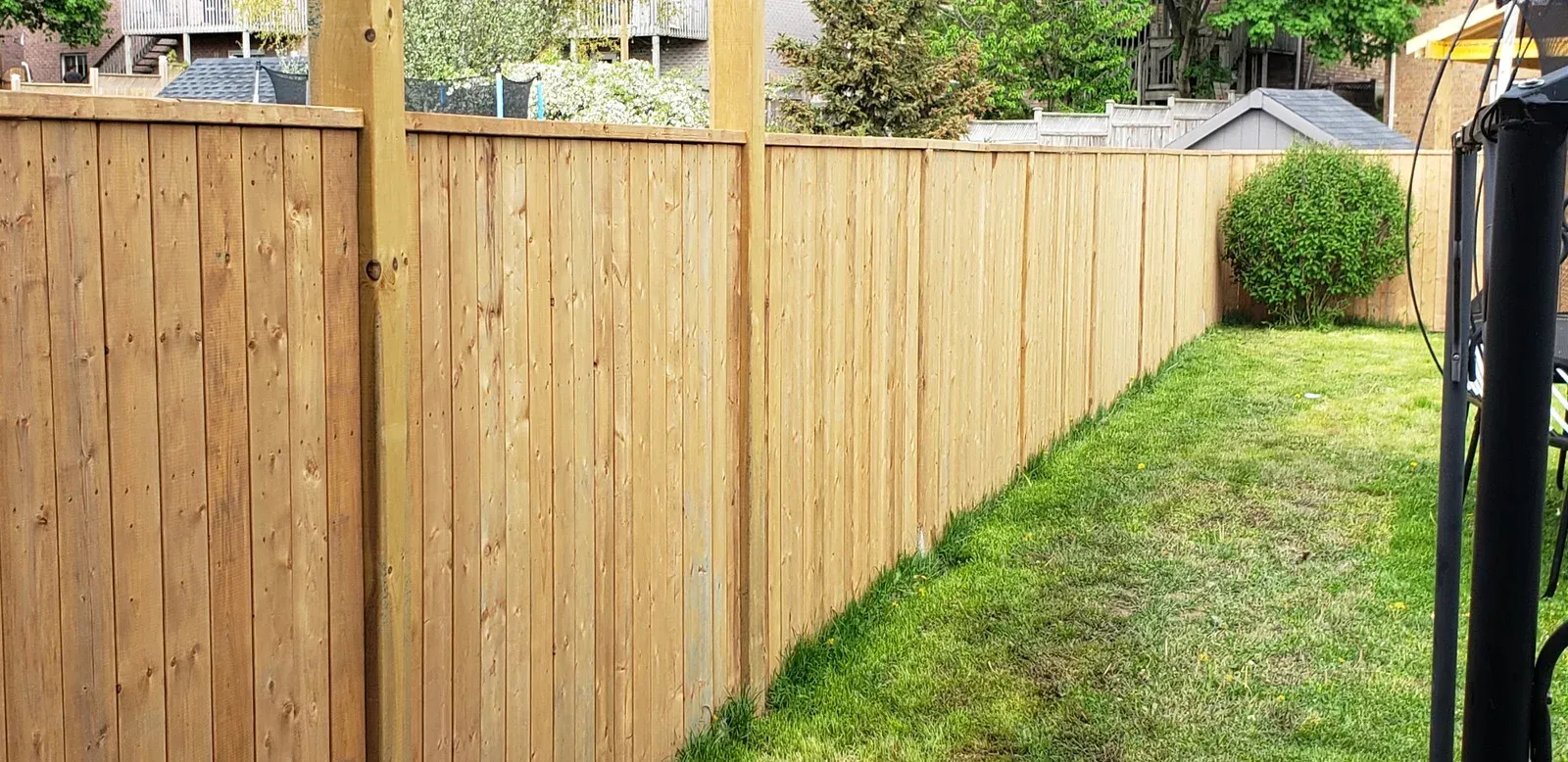 A wooden fence surrounds a lush green yard.