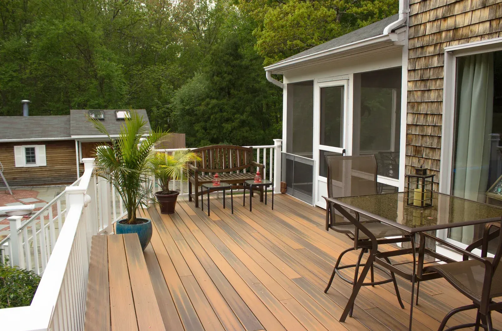 A patio with a grill and chairs in front of a house.