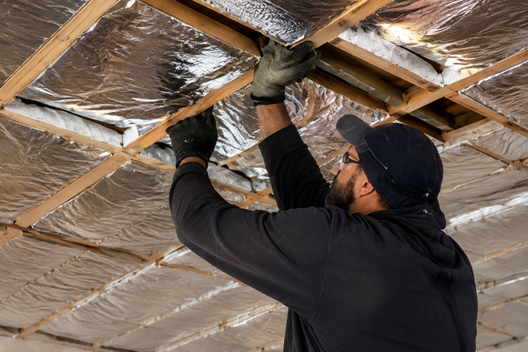Insulation installer putting blanket insulation into a dropped ceiling