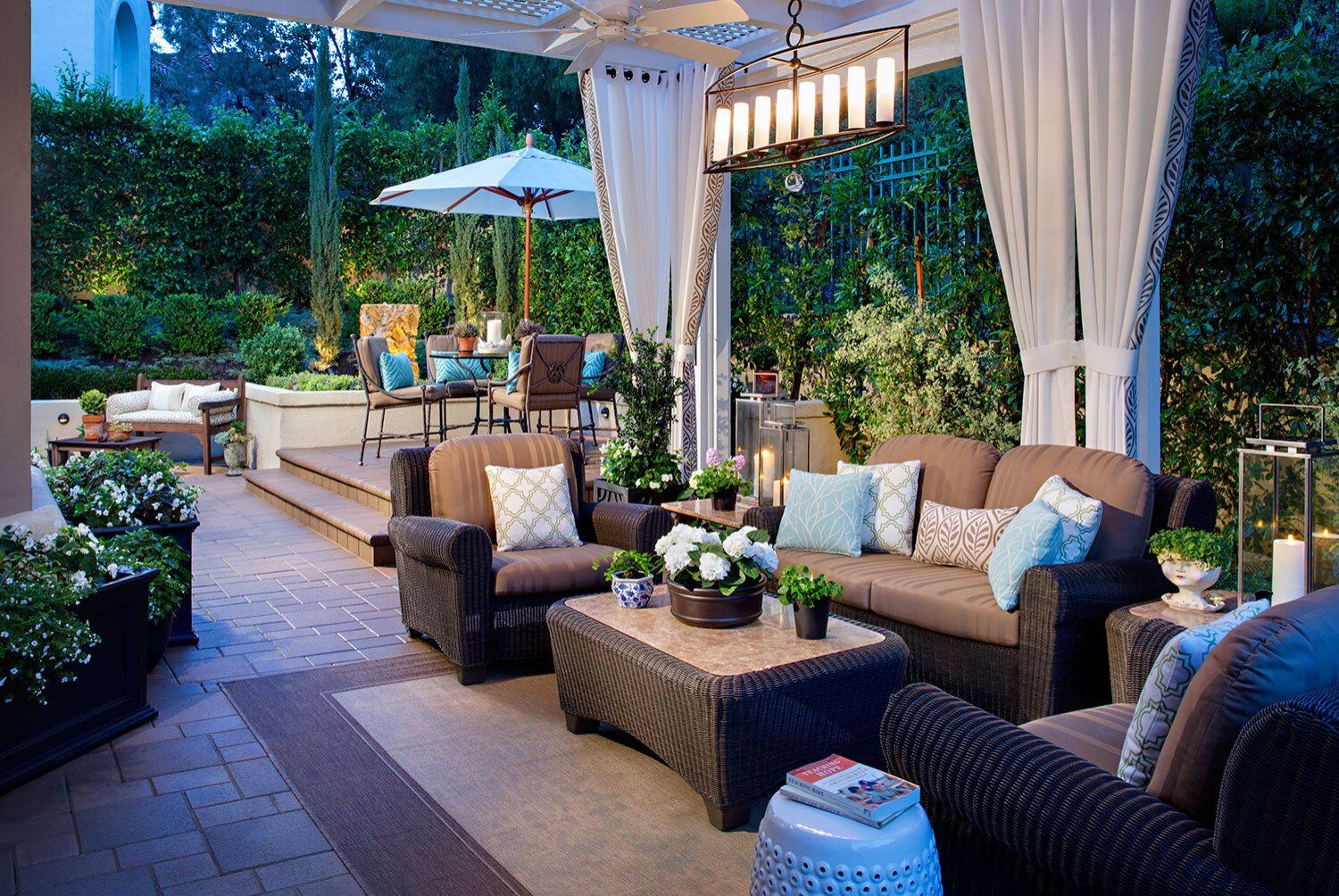 Outdoor patio with seating, curtains, and a dining area; evening lighting.