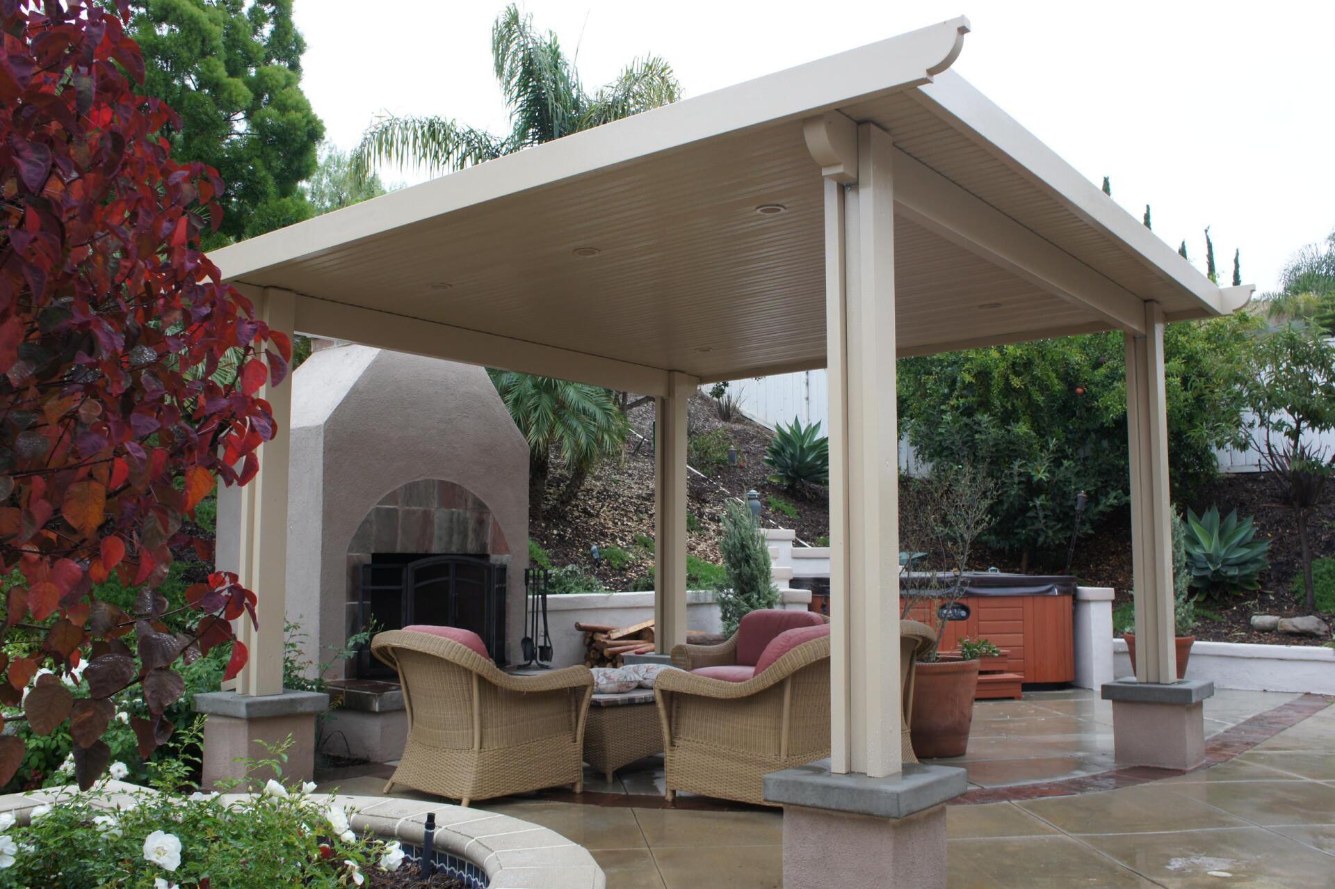 Beige patio cover over seating area with fireplace and hot tub in the background.