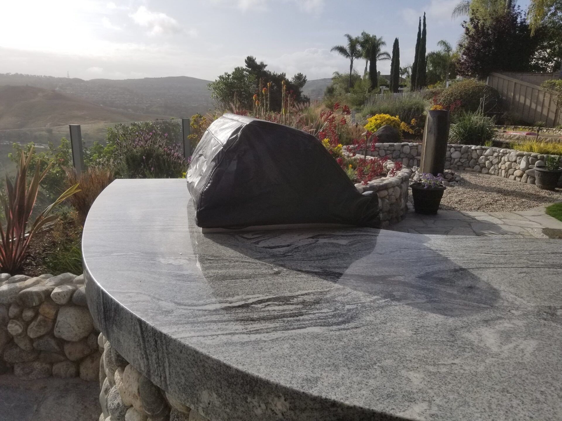 Granite countertop with covered grill, overlooking a hillside.