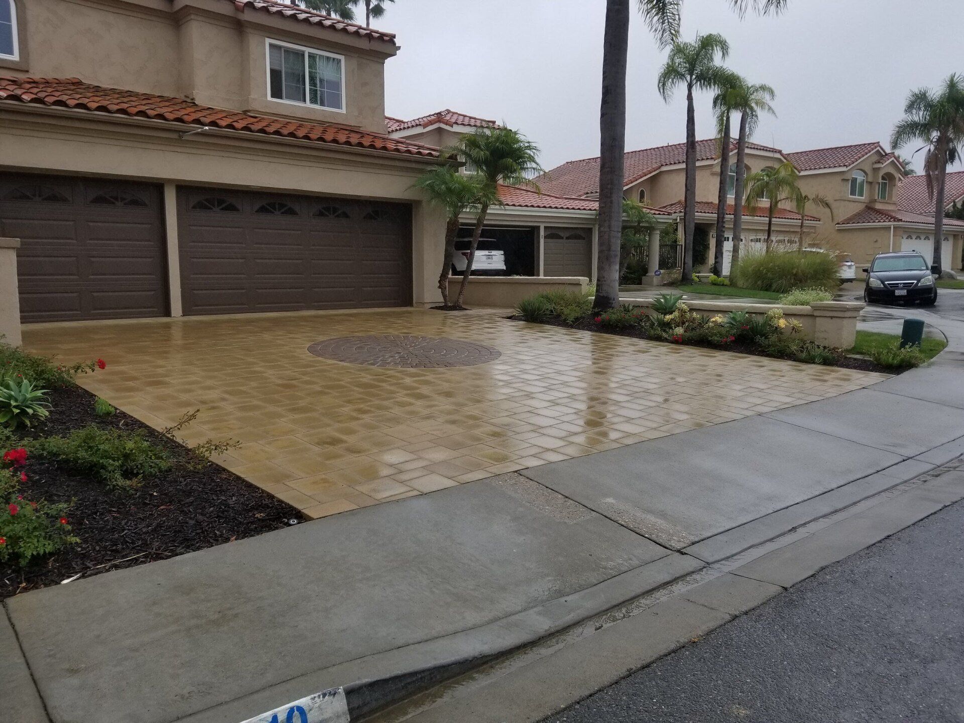 Driveway with brown brick pavers in front of a house.