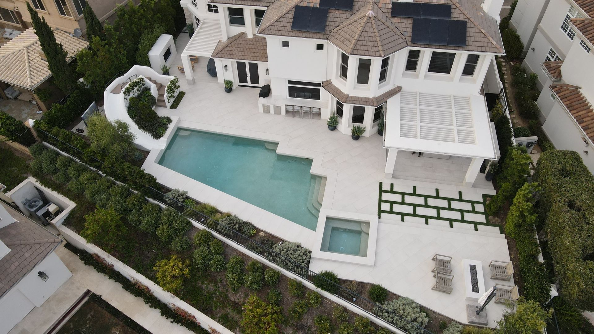 Aerial view of a luxurious white house with a pool and landscaped yard.