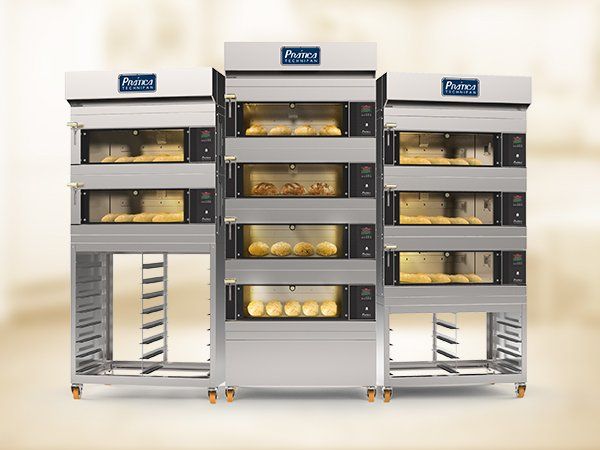 Una fila de hornos de acero inoxidable llenos de pan sobre una mesa.