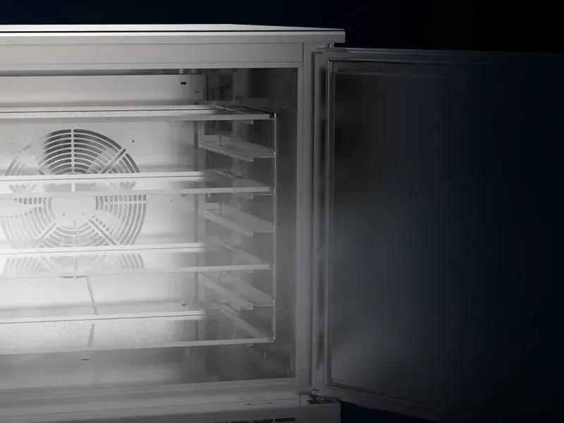 Uma geladeira com a porta aberta e um ventilador dentro dela.