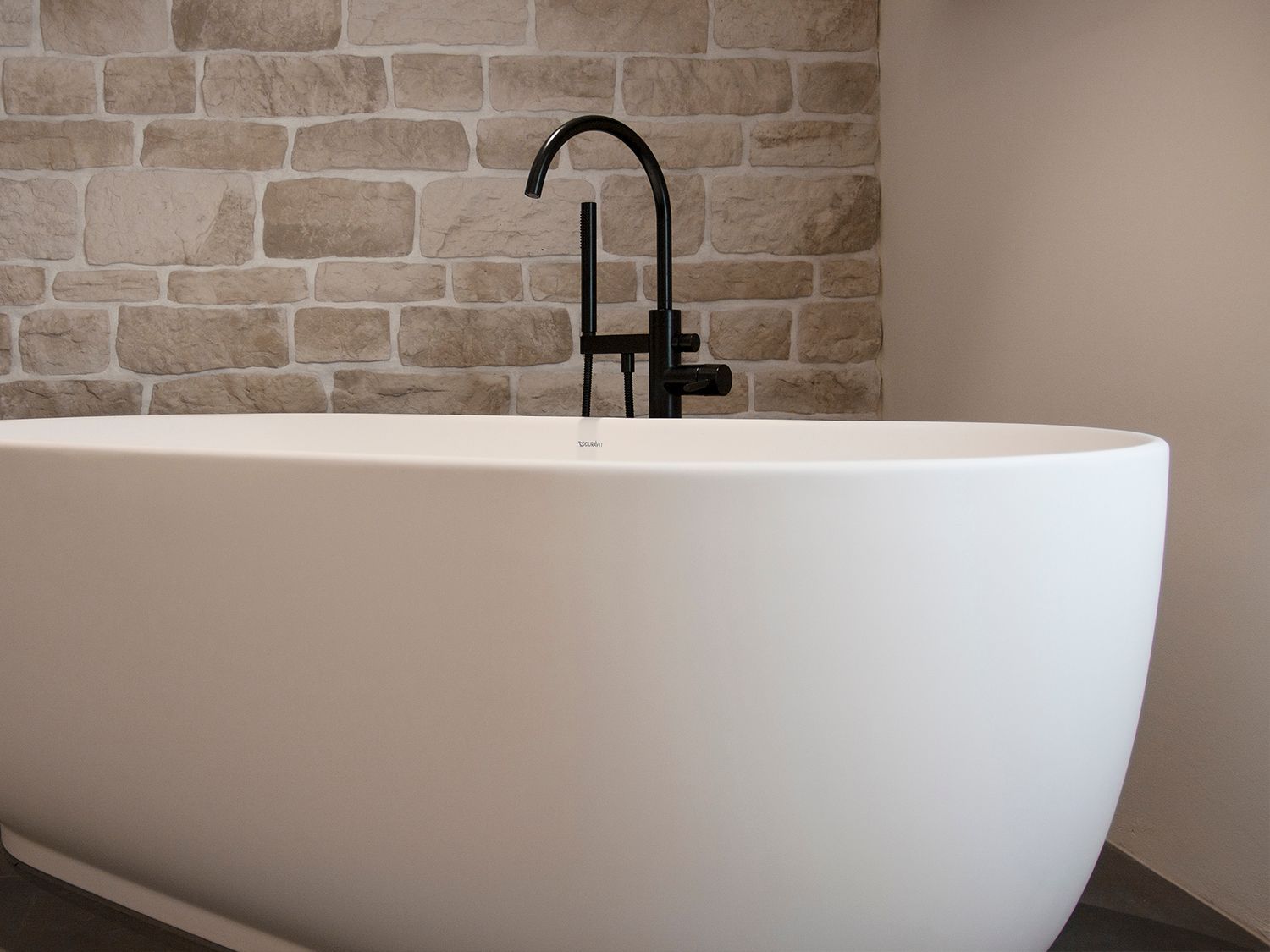 Eine weisse Badewanne mit einem schwarzen Wasserhahn in einem Badezimmer