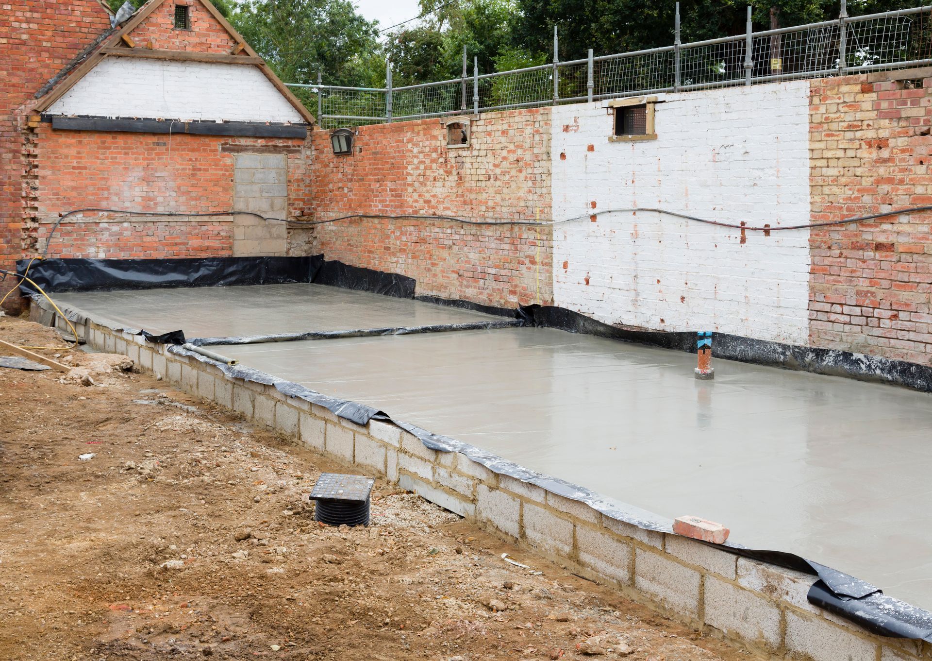 A concrete floor is being poured in front of a brick building.