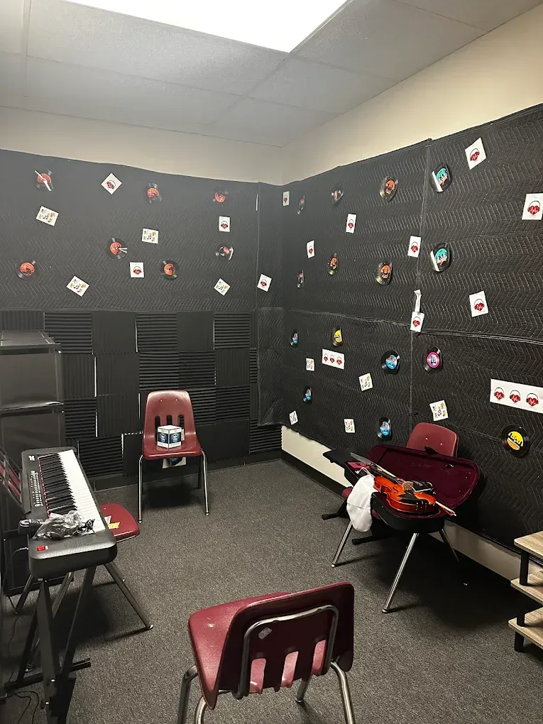 A music room with a piano , chairs , and a guitar.