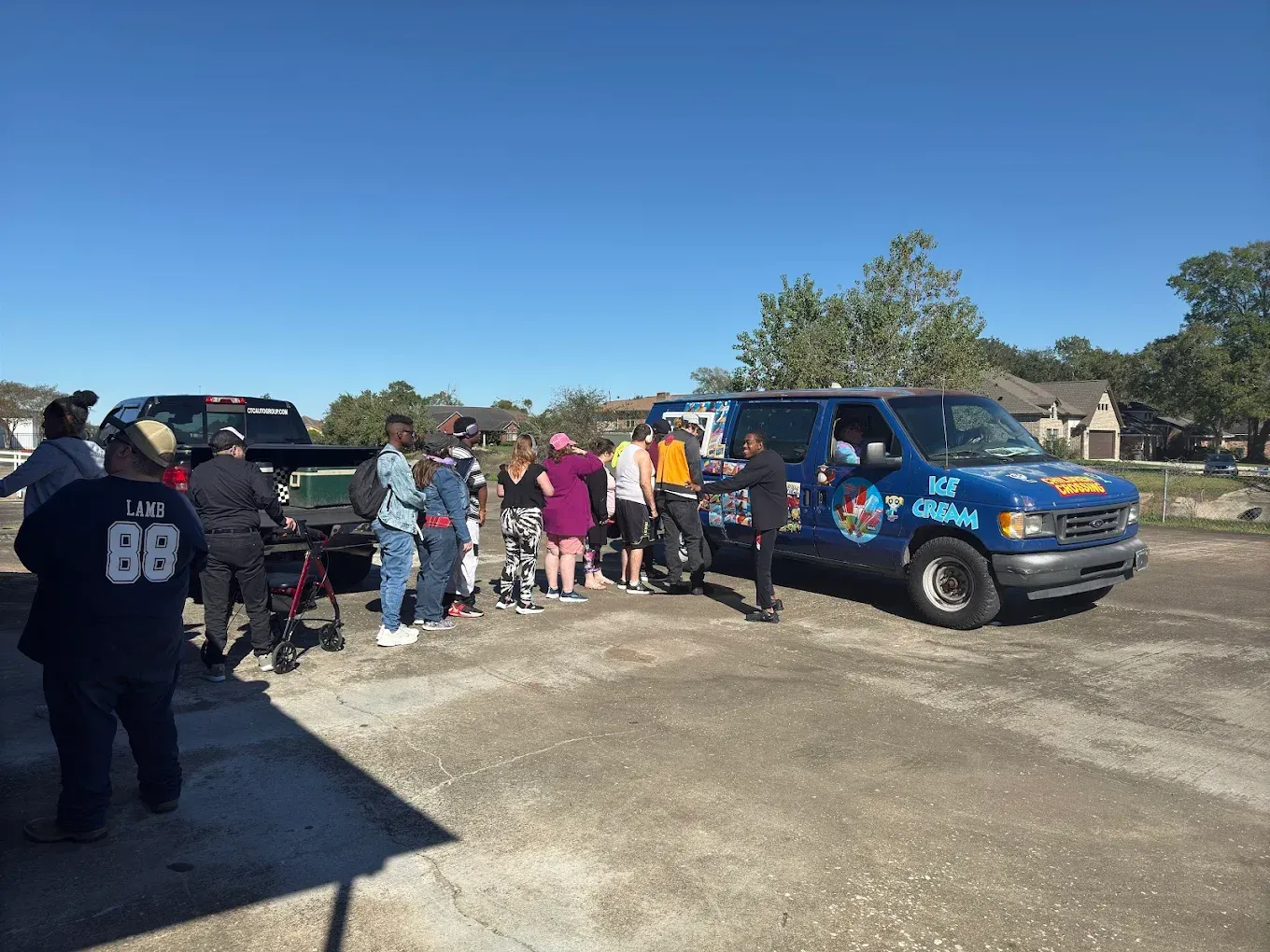 A group of people are standing in front of a blue van.
