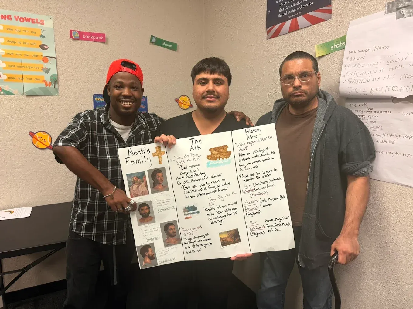 Three men are standing next to each other holding a poster.