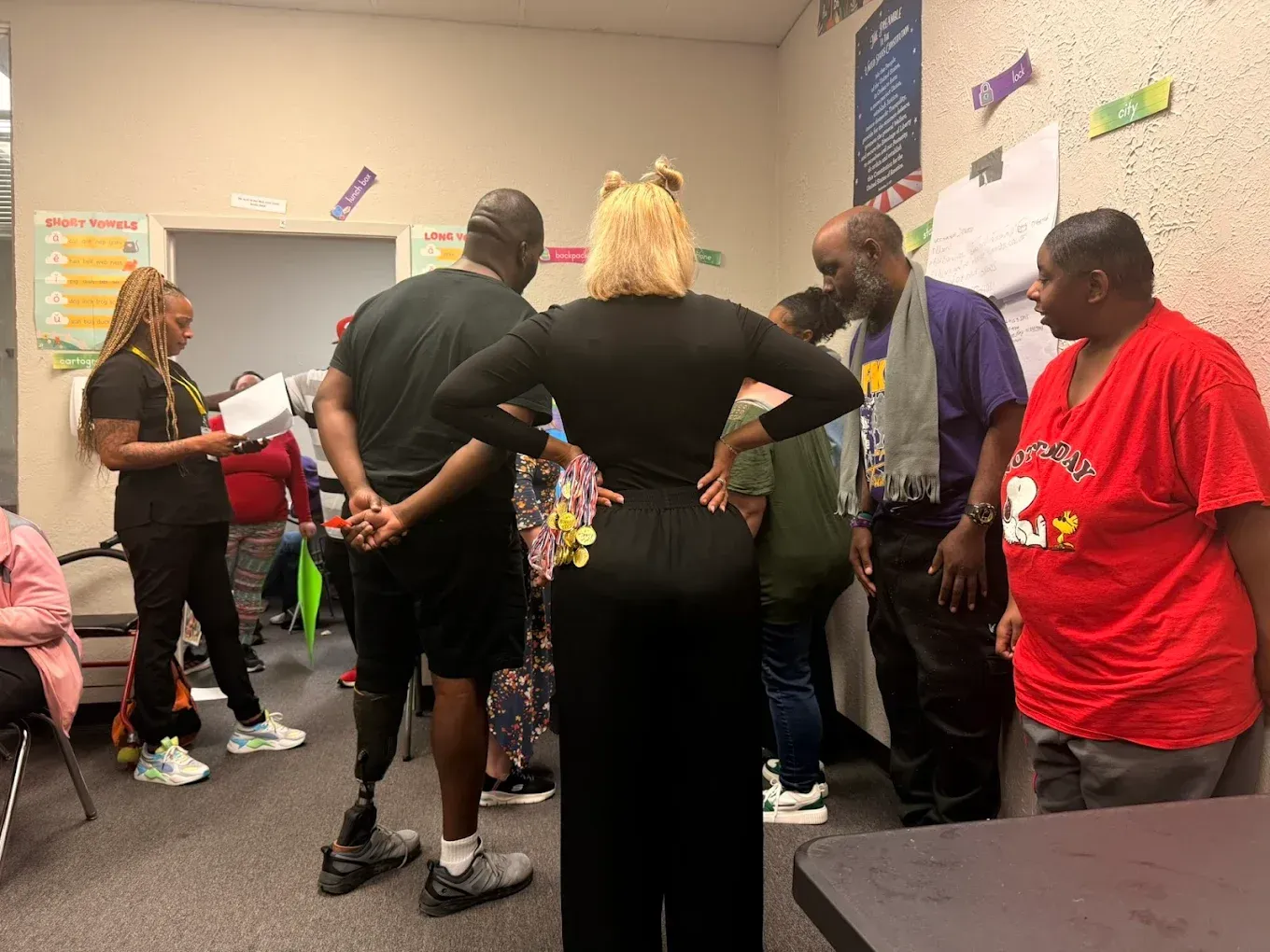 A group of people are standing in a room with their hands on their hips.