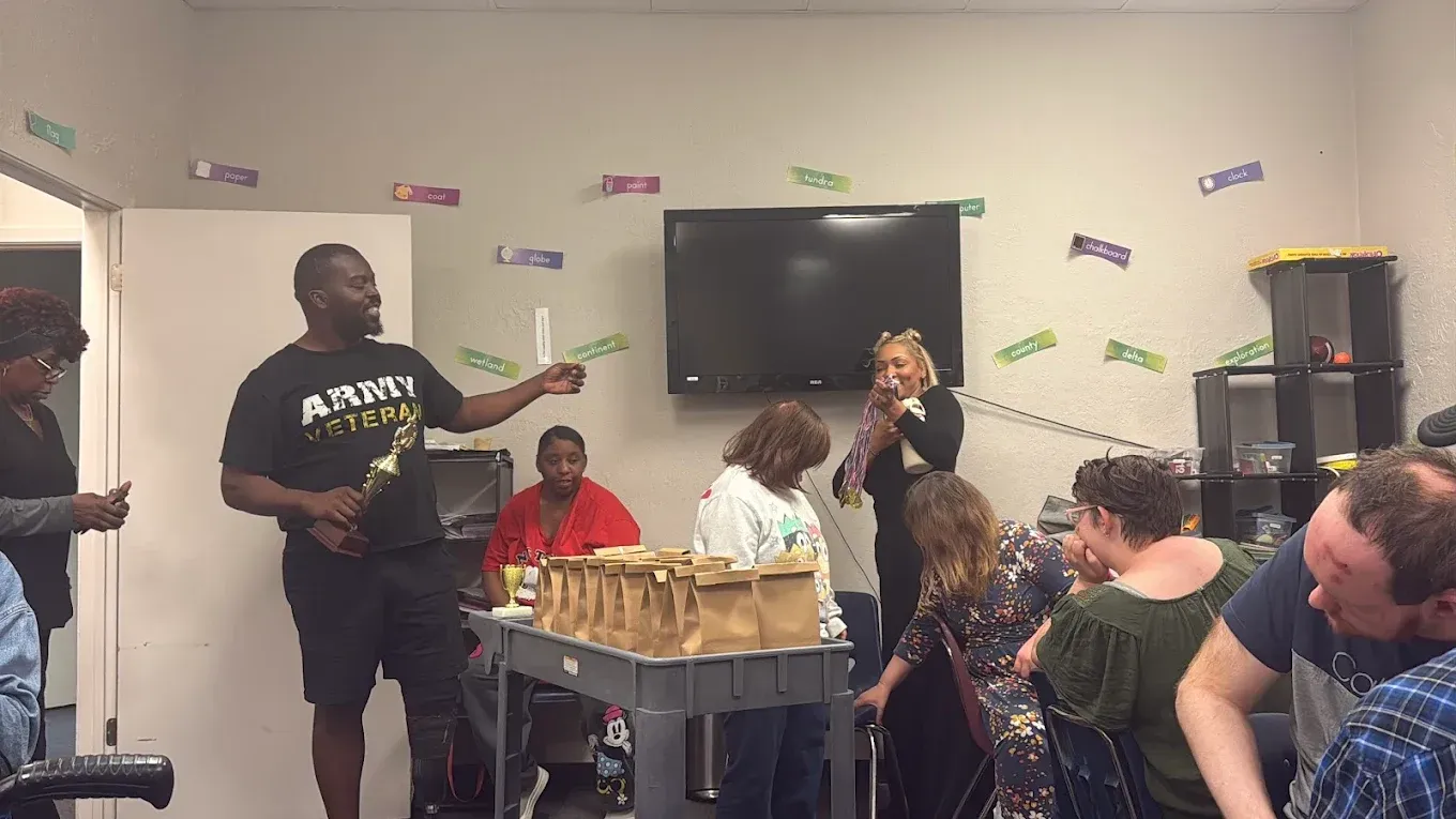 A man is standing in front of a group of people in a room.