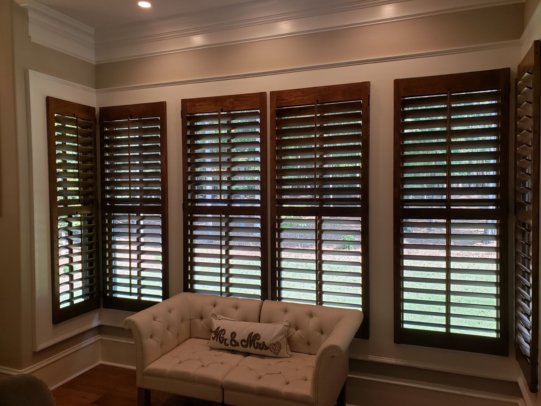 A living room with a couch and shutters on the windows
