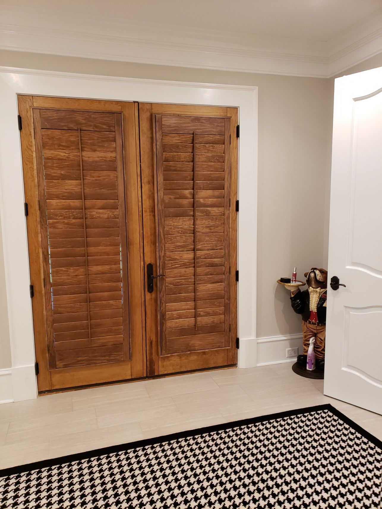 A room with two wooden doors and a black and white rug.
