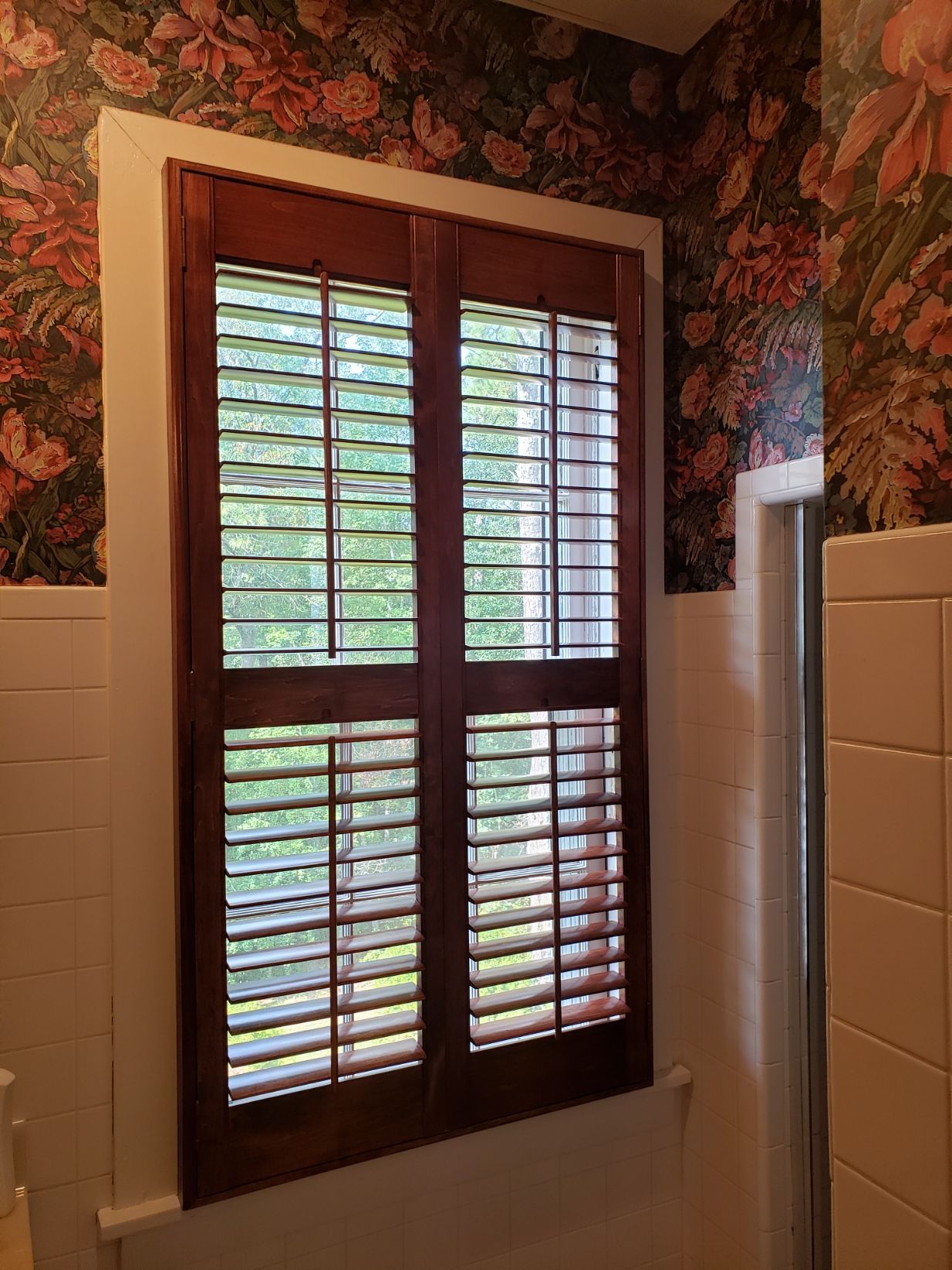 A bathroom with a window with shutters on it.