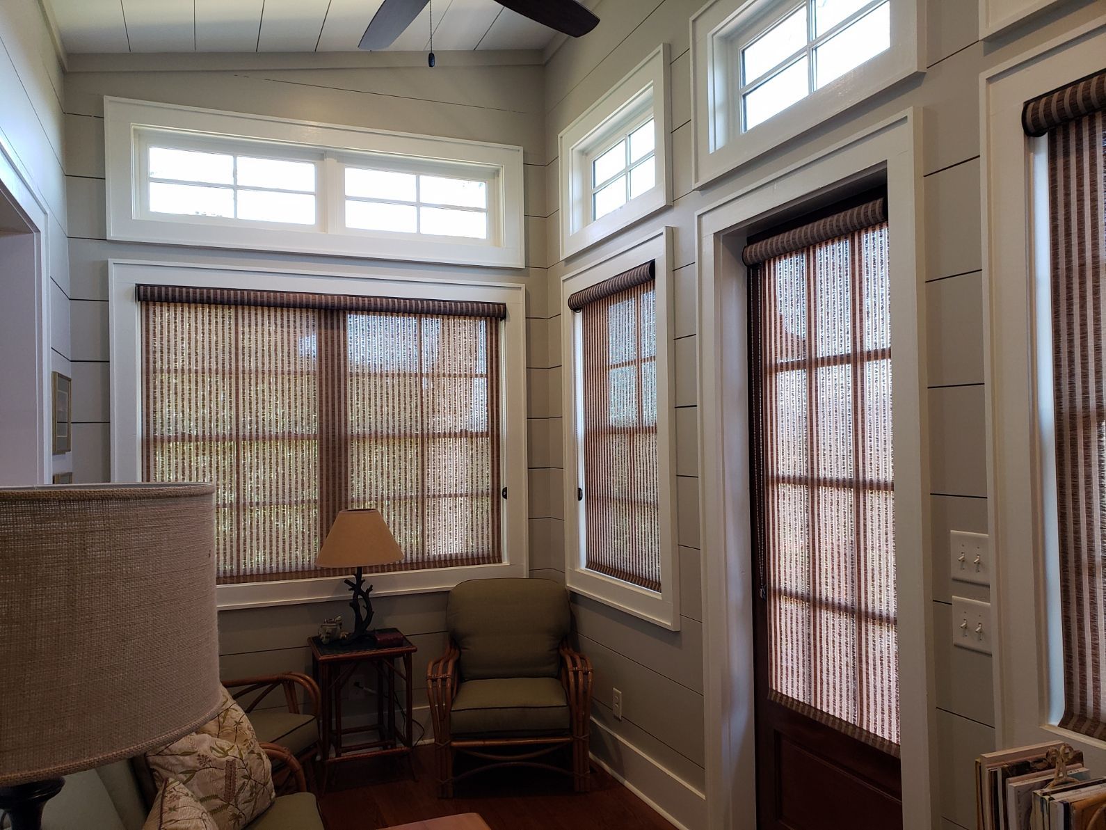 A living room with a lot of windows and a ceiling fan