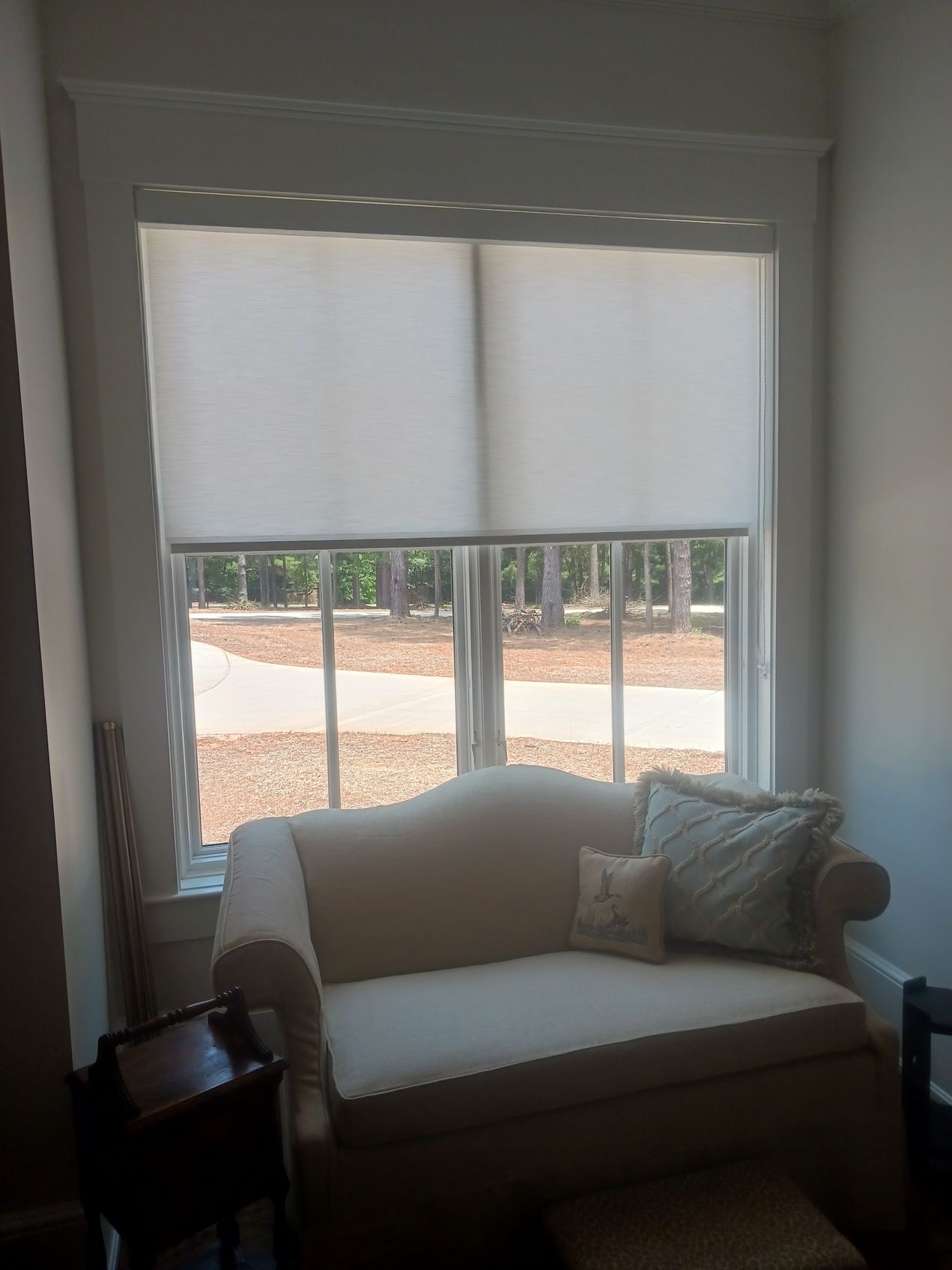 A living room with a couch and a window with white blinds.
