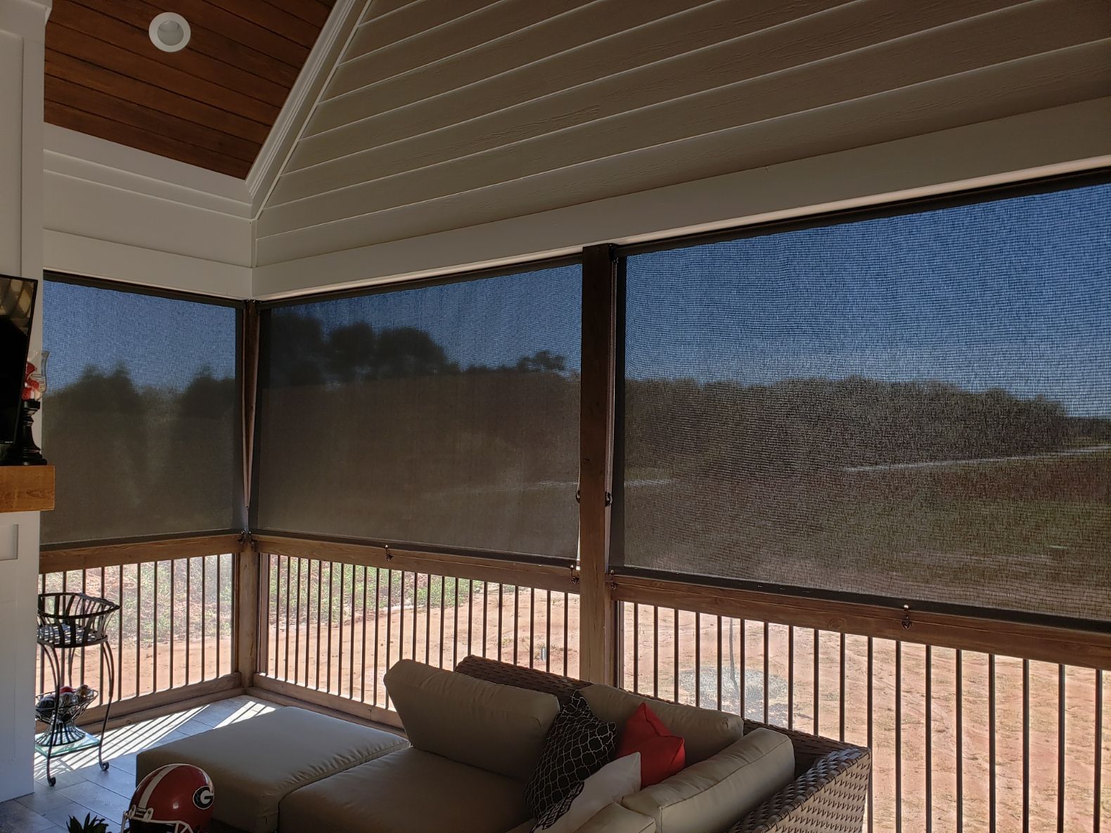 A screened in porch with a couch and a fireplace