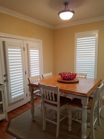A dining room with a wooden table and white chairs
