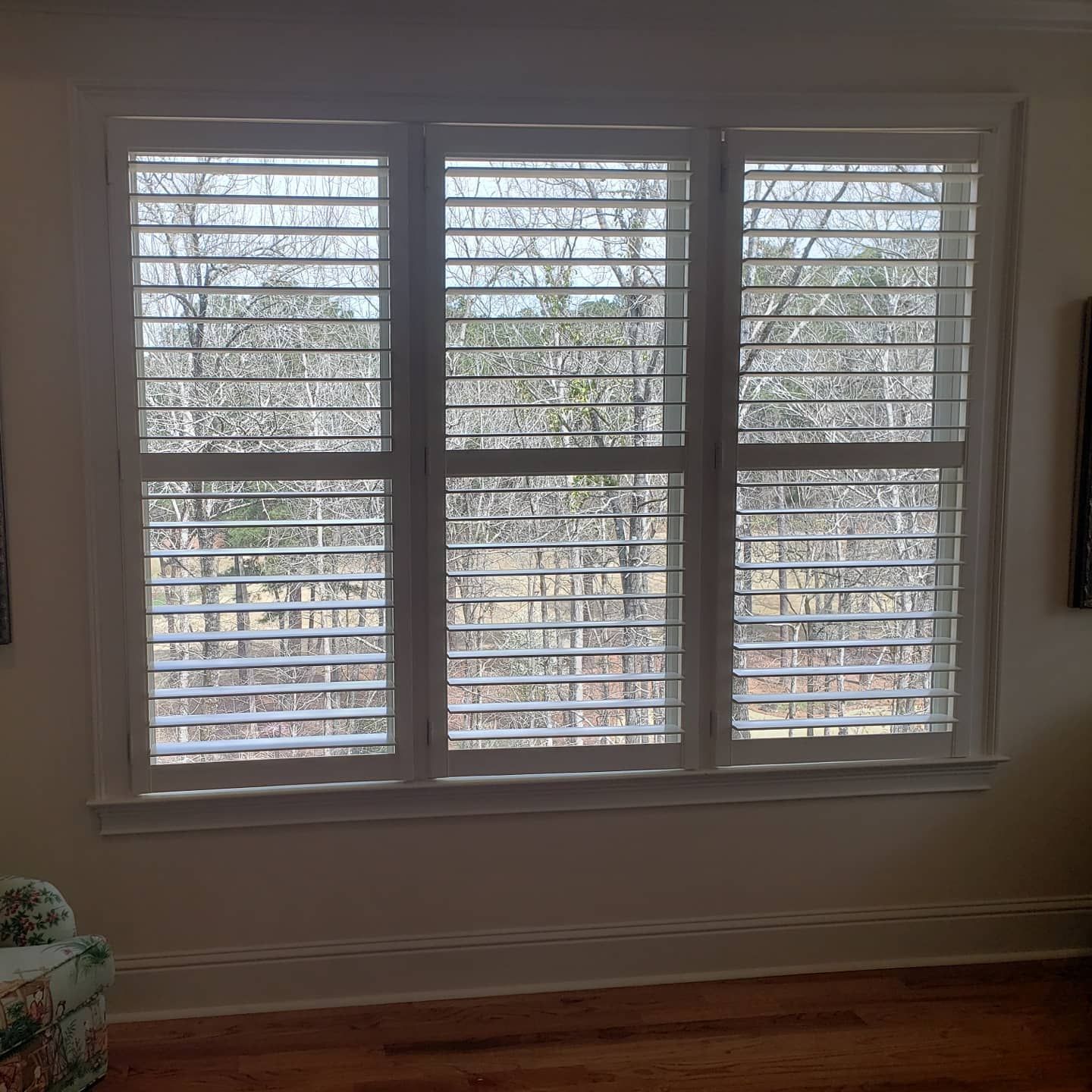 A living room with a large window with shutters on it.