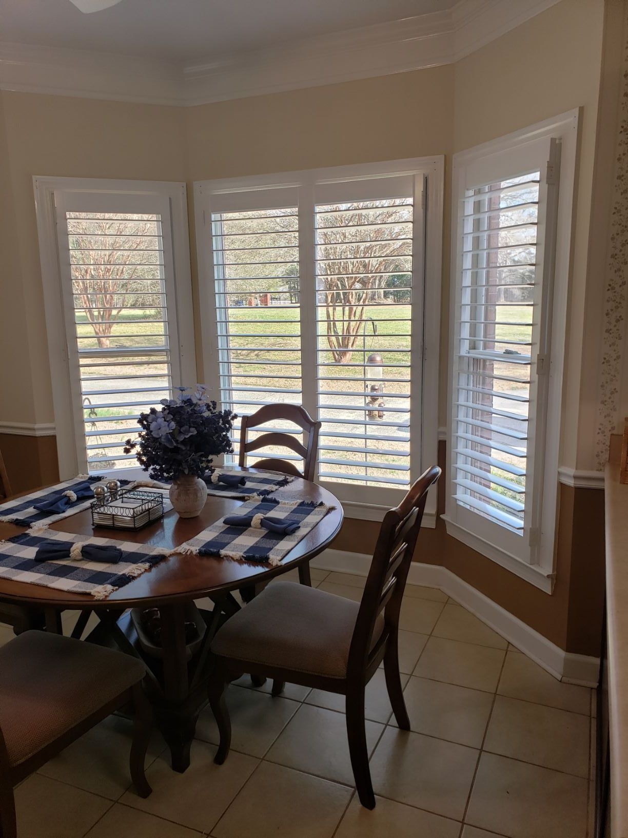 A dining room with a table and chairs and shutters on the windows.