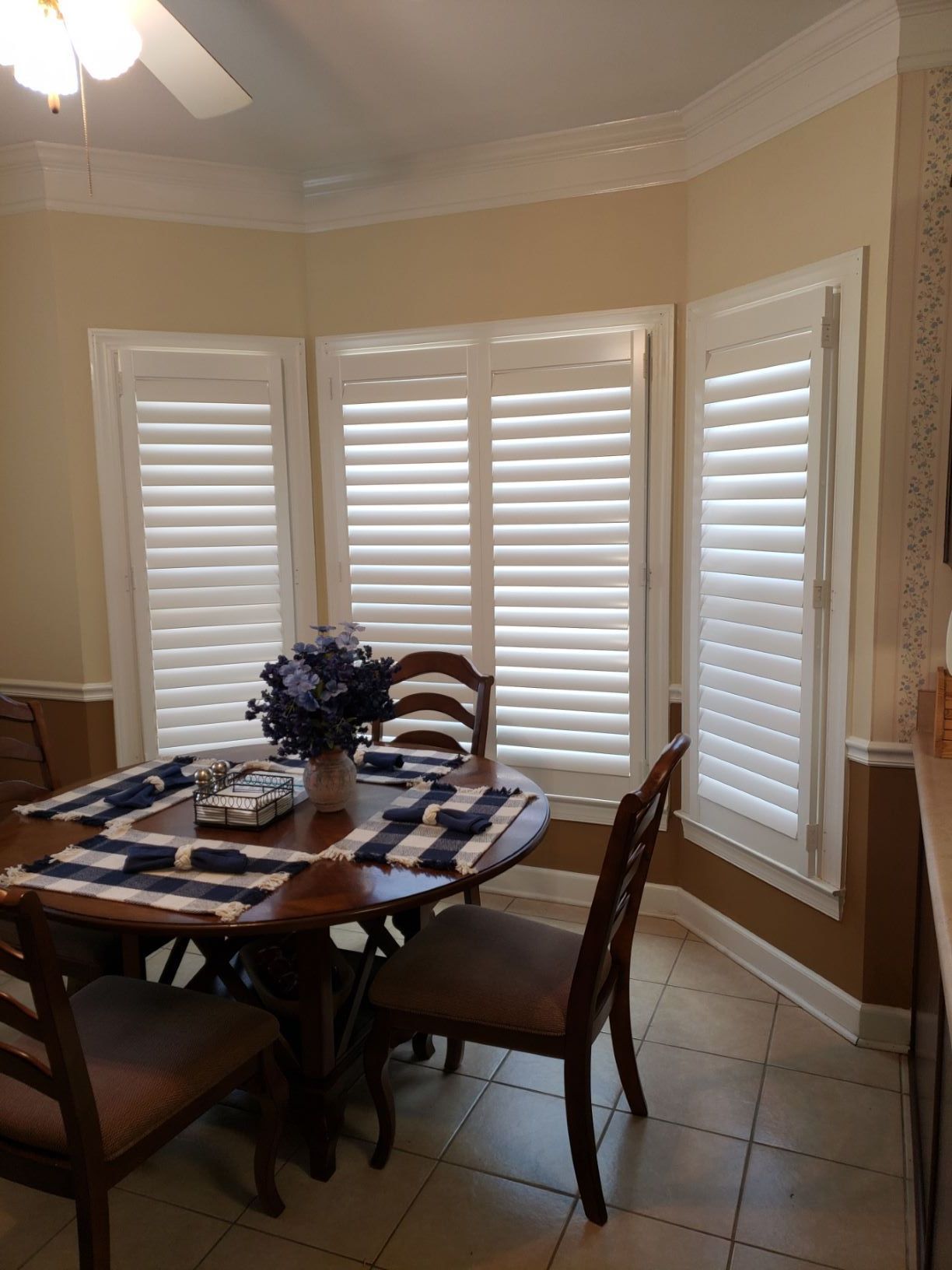 A dining room with a table and chairs and shutters on the windows.