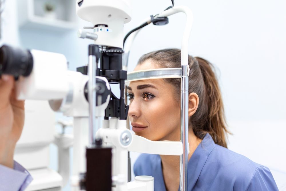 Patient at an Eye Exam Using a Slit Lamp With an Optometrist Nearby — Peninsula Eyecare Izzards Optometrists in Woy Woy, NSW