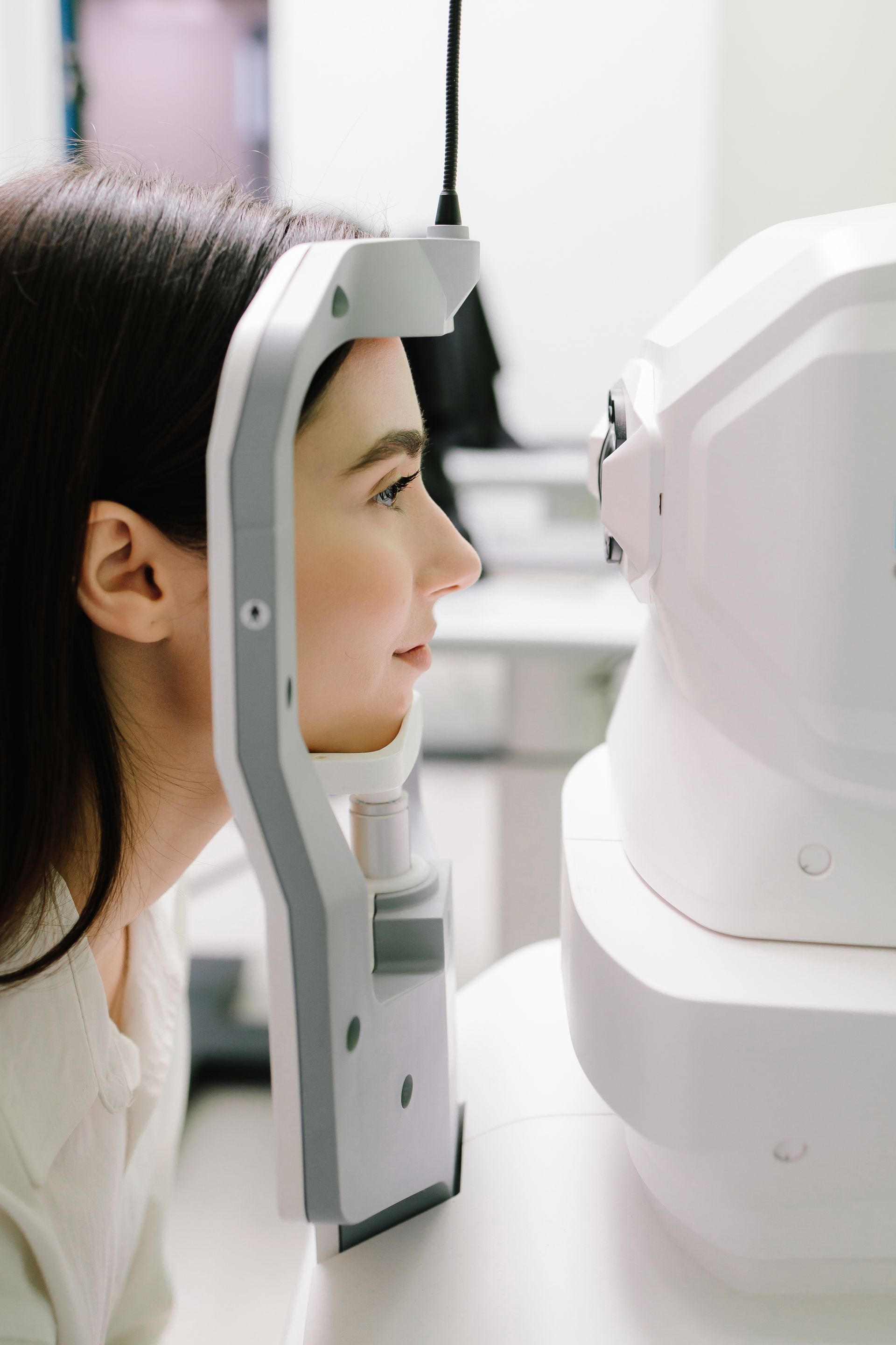 A Person Rests Their Chin and Forehead on an Eye Examination Machine — Peninsula Eyecare Izzards Optometrists in Kariong, NSW