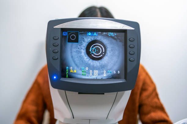A Person Sits at an Eye Exam Machine — Peninsula Eyecare Izzards Optometrists in Woy Woy, NSW
